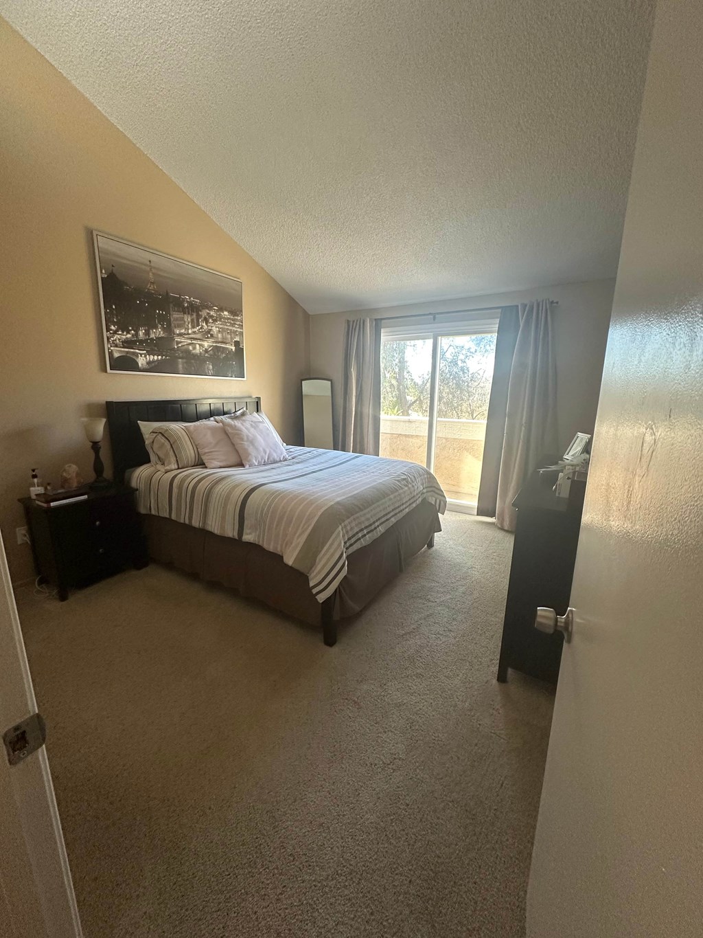 A bedroom with a large bed and a picture on the wall.