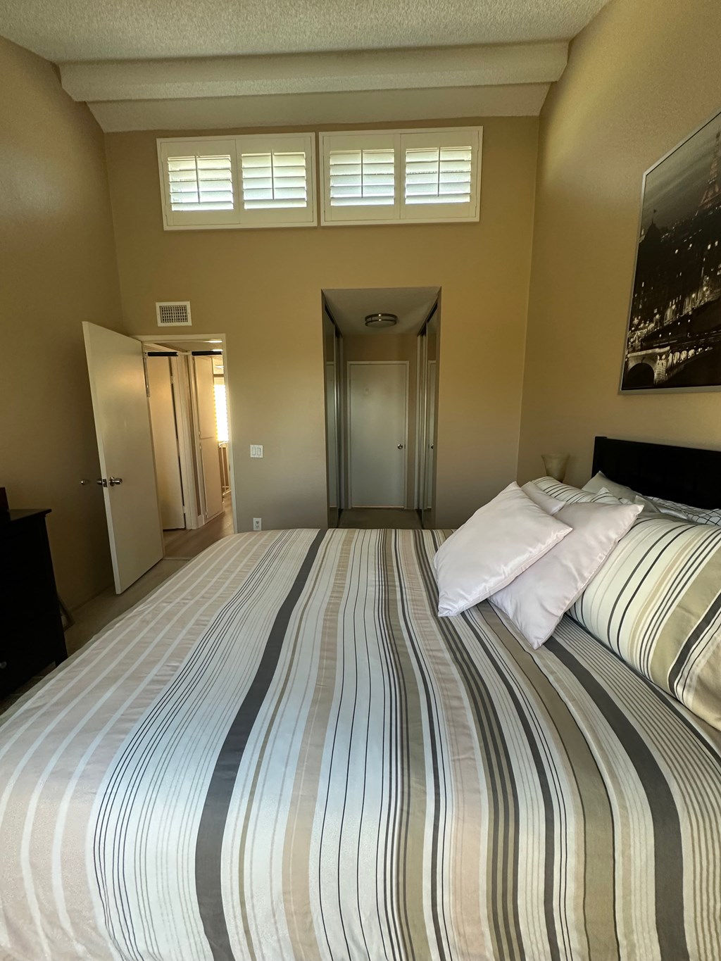 A bedroom with a bed, dresser, and a painting on the wall.