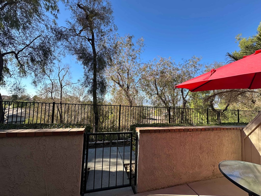 A patio with a table and chairs under a red umbrella.