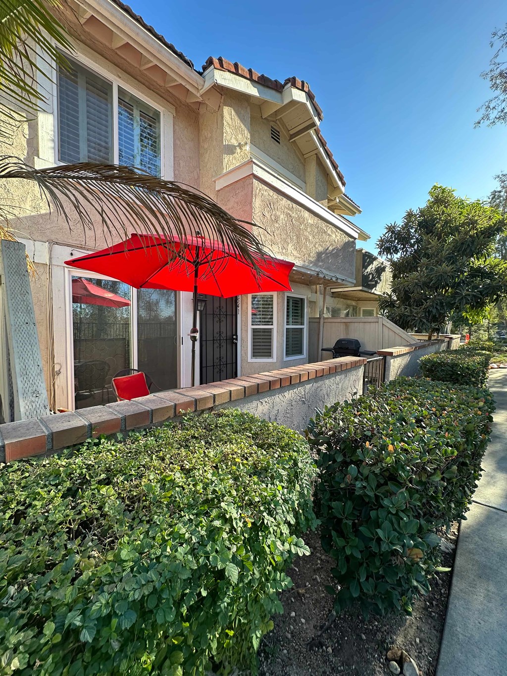 A red umbrella is on the patio of a house.