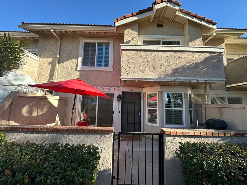 A house with a red umbrella on the patio.