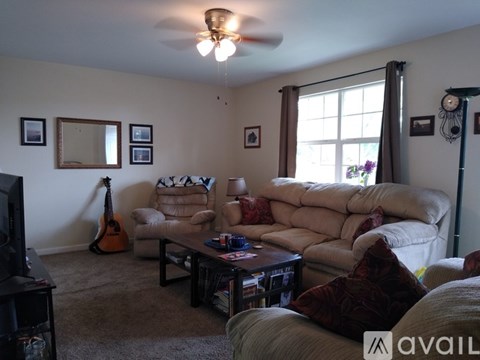A living room with a couch, a chair, a coffee table, a television, and a guitar.