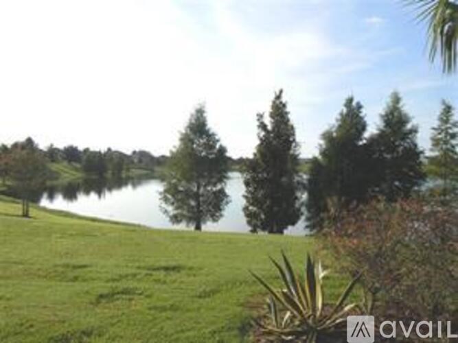 A grassy field with a lake and trees in the distance.