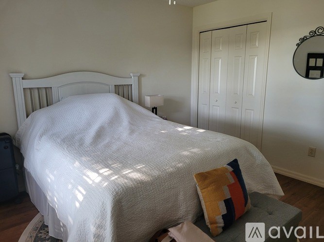 A bedroom with a white bed and a pillow on it.