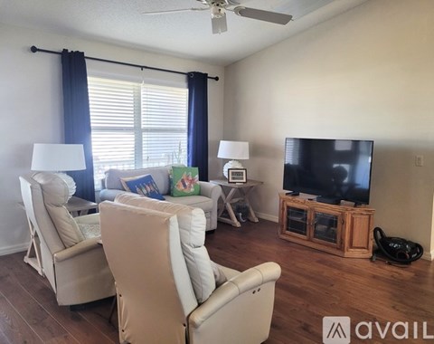 A living room with a television, two chairs, and a table with a lamp.