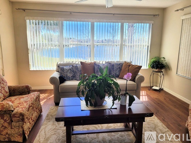 A living room with a couch, chair, and potted plant.