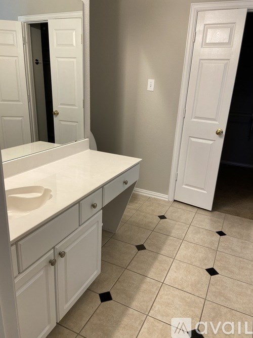 A bathroom with a white sink and cabinets.