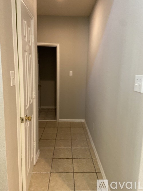A hallway with a door on the left and a wall on the right.
