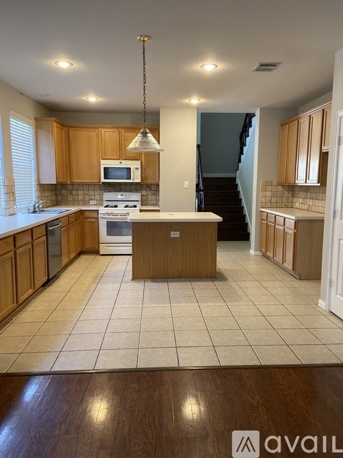 A kitchen with wooden cabinets and a white microwave above the stove.