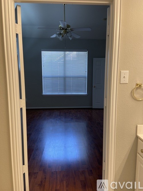 A room with a ceiling fan and wooden floors.