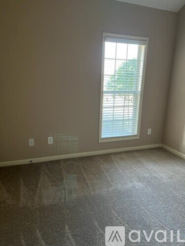 A room with a window and a carpeted floor.