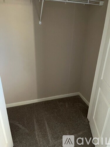 A small, empty room with a carpeted floor and a white door.