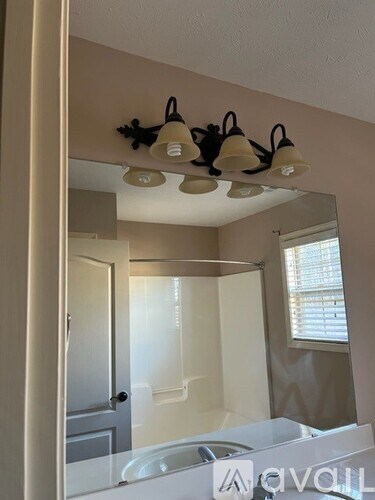 A bathroom with a mirror, light fixture, and a sink.