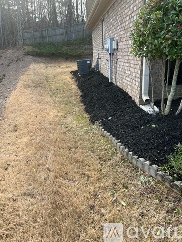 A black mulch bed is in front of a house.
