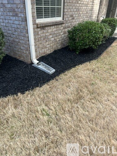 A white pipe is sticking out of a black mulch bed.