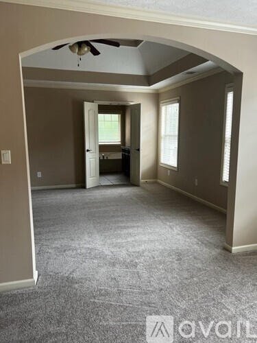 A room with a carpeted floor and a ceiling fan.