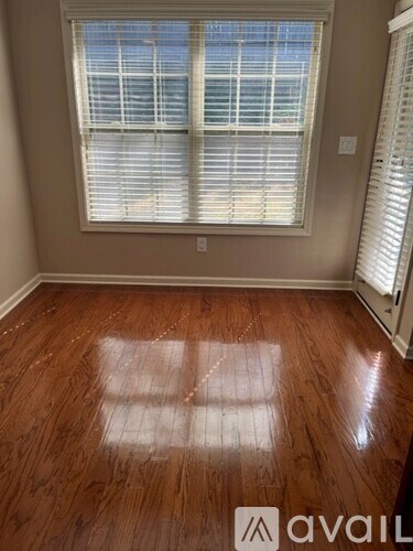 A room with wooden flooring and a window with blinds.