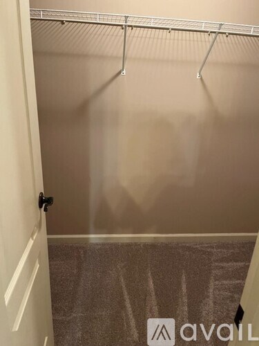 A white door is on the left of a hallway with a metal rack on the right.