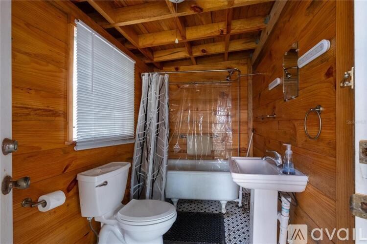 A wooden bathroom with a toilet, sink, and shower.