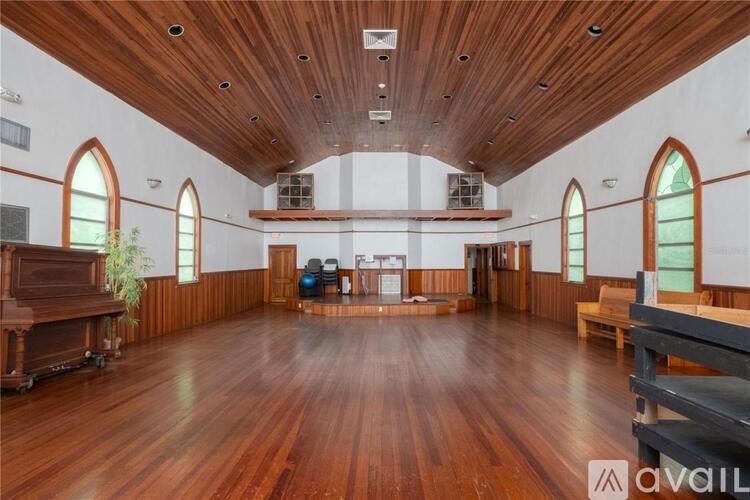 A large room with wooden floors and arched windows.