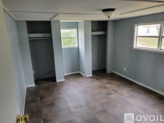 A room with grey walls and a wooden floor is available for rent.