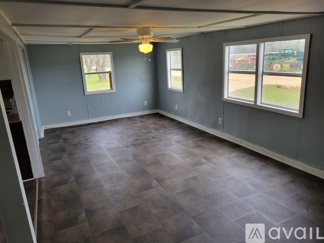 A room with a ceiling fan and three windows.
