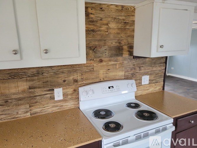 A white stove is in a kitchen with wooden walls.