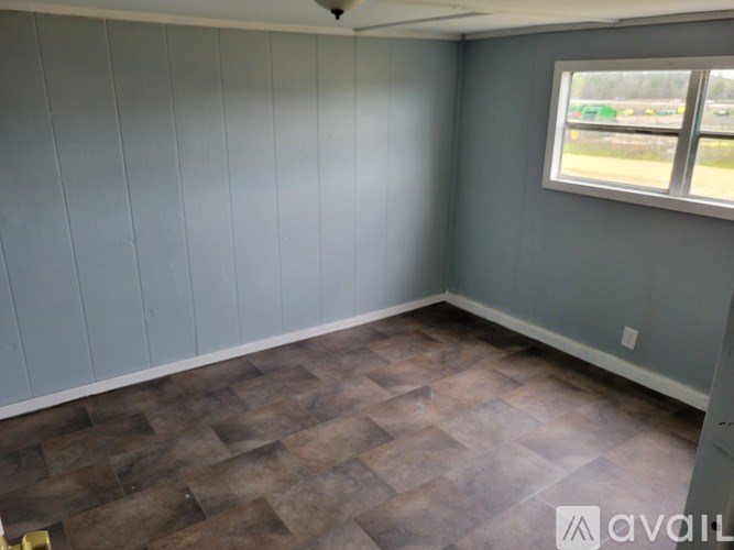 A room with wooden flooring and a window showing an outdoor scene.