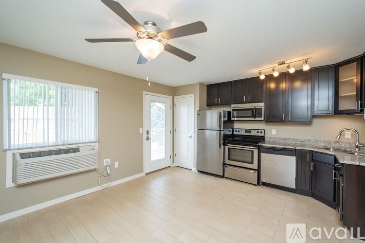 A kitchen with a fan on the ceiling and a window with blinds.