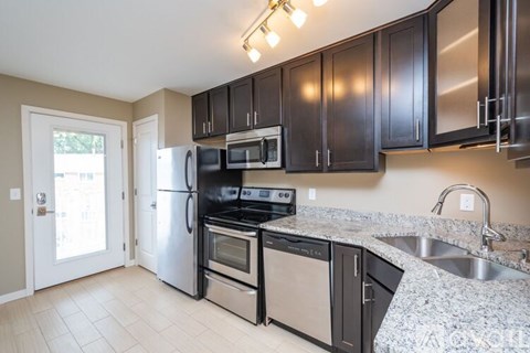 A kitchen with black cabinets and stainless steel appliances.