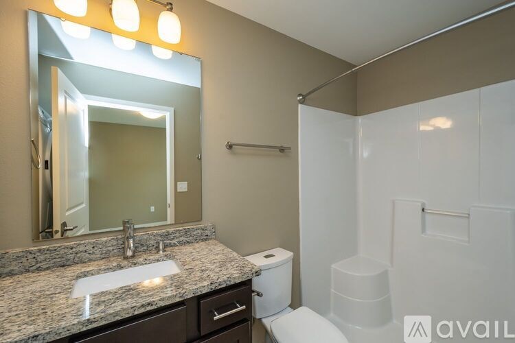 A bathroom with a granite countertop and a large mirror.