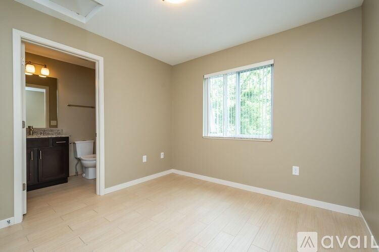 A room with beige walls and a window with a view of greenery outside.