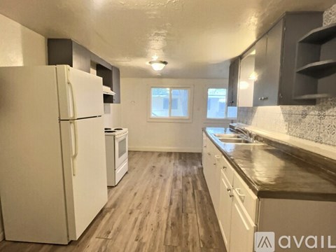 A kitchen with a white refrigerator and wooden floors.