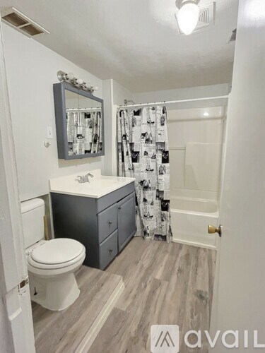 A bathroom with a toilet, sink, and mirror.