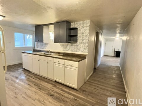 A kitchen with white cabinets and a wooden floor.