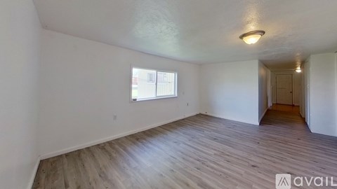 A room with wooden flooring and a window with a view of a building outside.