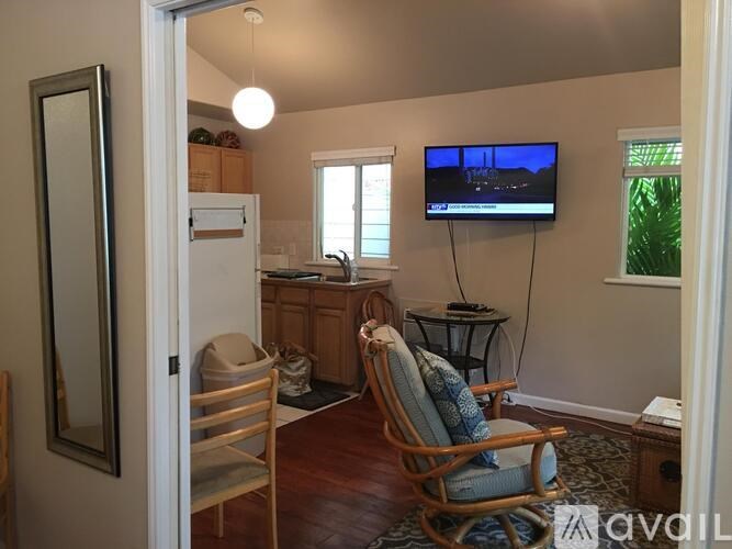 A living room with a TV on the wall and a chair in front of it.