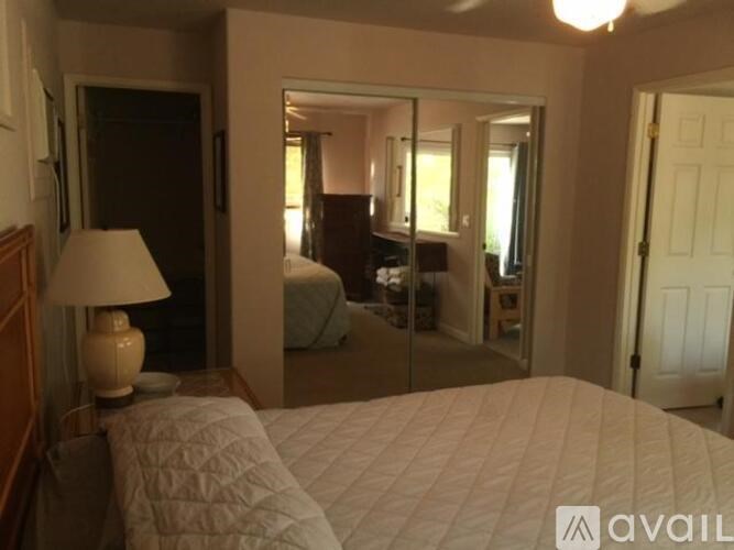 A bedroom with a large bed and a lamp on the nightstand.