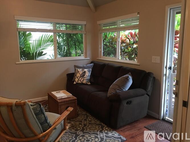 A living room with a brown couch and a wooden chair.