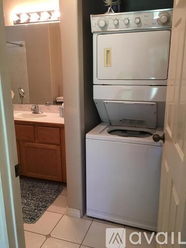 A white dishwasher is in a bathroom next to a sink.