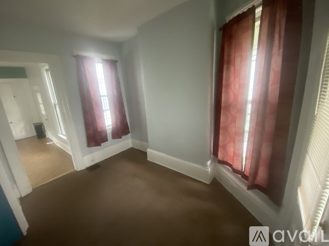 A room with brown carpet and red curtains.