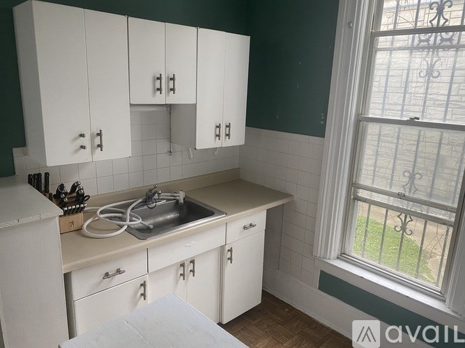A kitchen with white cabinets and a window.