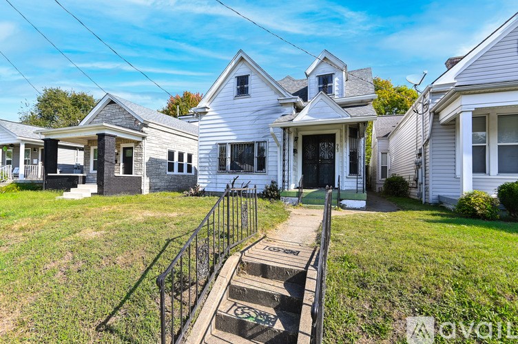 A white house with a black metal railing and steps leading to the front door.