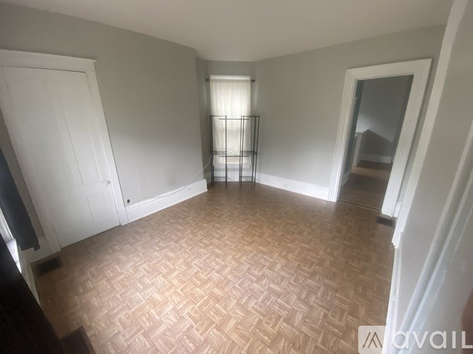 A room with a herringbone patterned floor and a window with blinds.
