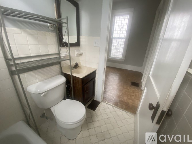 A bathroom with a toilet, sink, and a mirror.