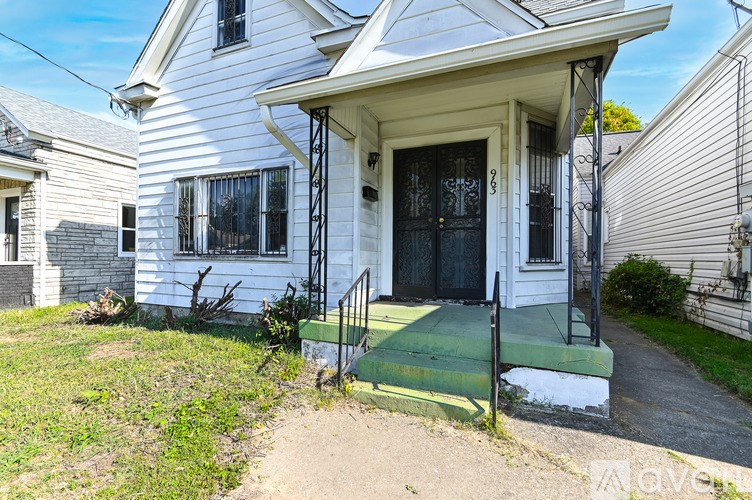 A white house with a black door and a green staircase leading to the entrance.