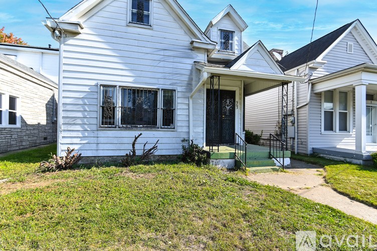 A white house with a black door and a small front yard.