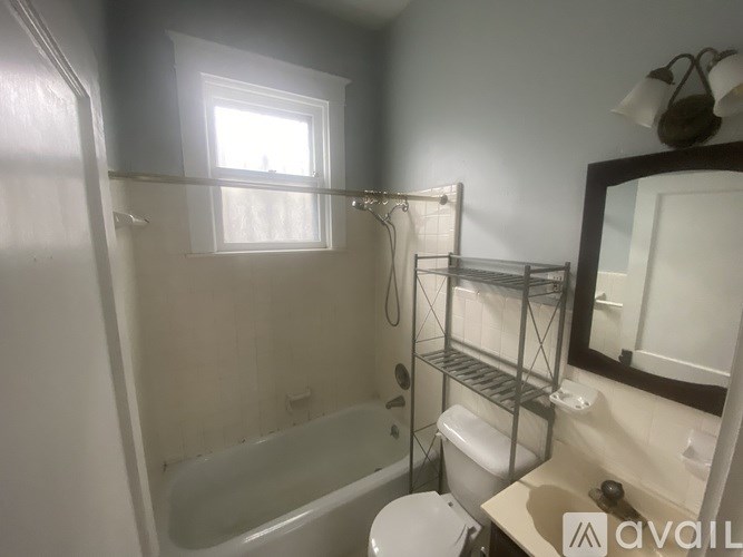 A bathroom with a tub, toilet, sink, and mirror.