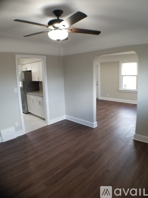 A room with a ceiling fan and wooden flooring.