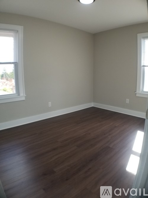 A room with wooden floors and two windows.